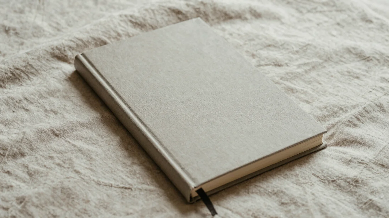 Textured hardcover devotional journal resting on a soft linen fabric under soft daylight